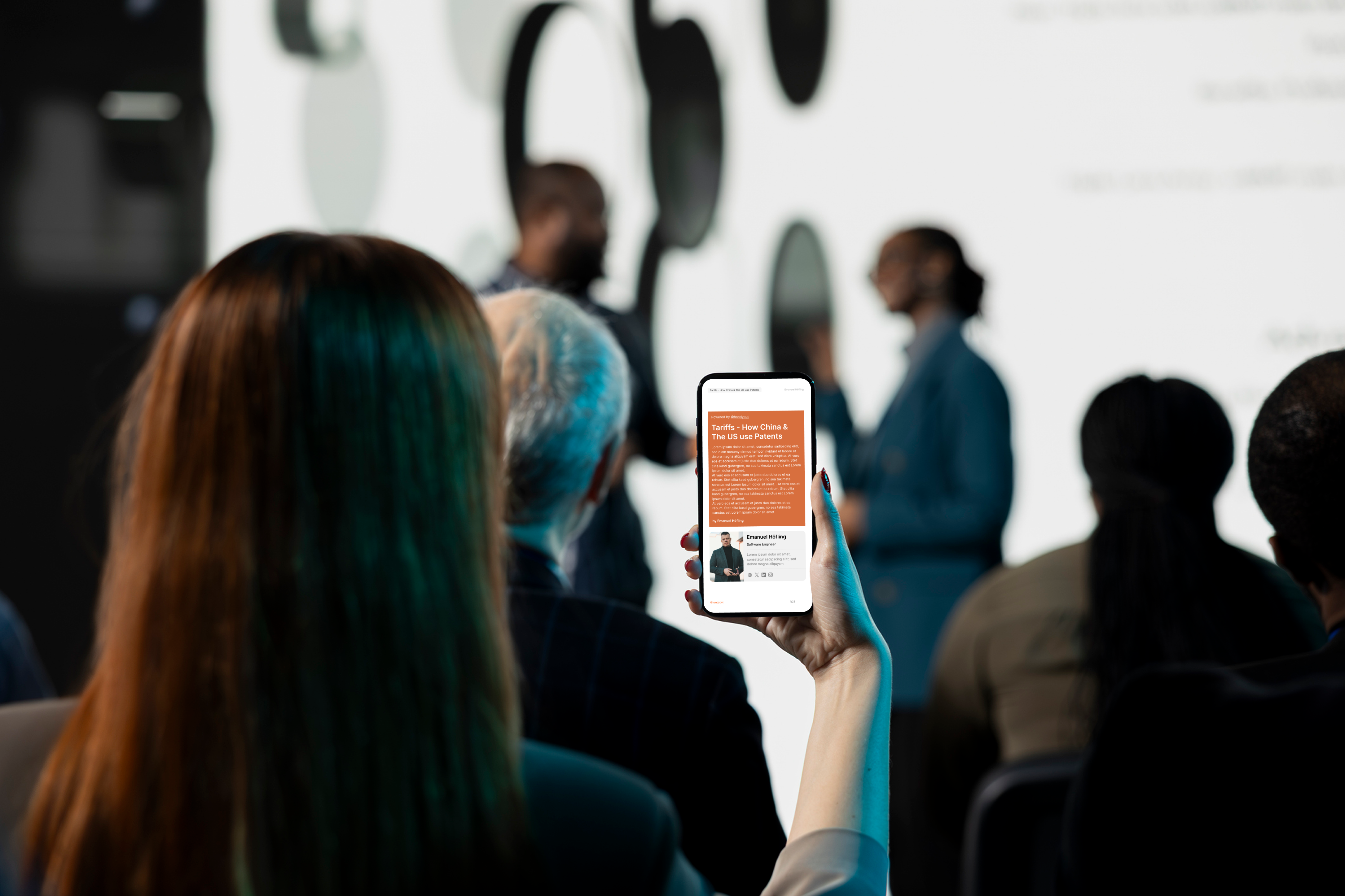 An audience member reading a Handyout on her phone during a talk